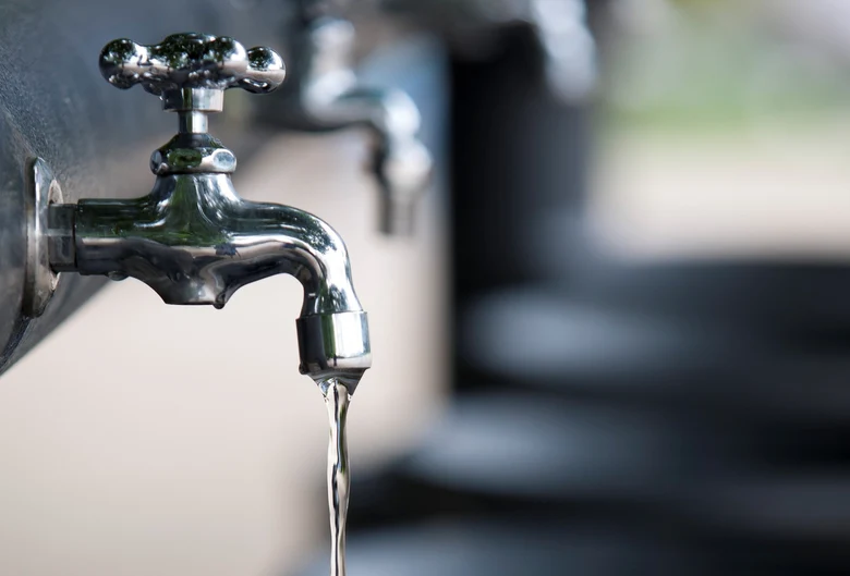 Laufender, metallener Wasserhahn mit schwarzer Schale